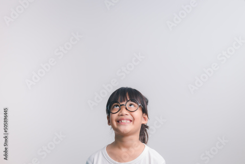 cute little preschooler girl isolated on grey studio background wear glasses look at camera, small child try spectacles at opticians, kid eyesight correction treatment concept