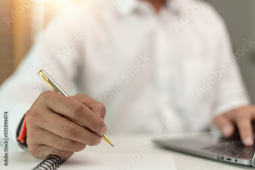 man writing making list taking notes in notepad working or learning on laptop indoors- educational course or training  seminar  education online concept
