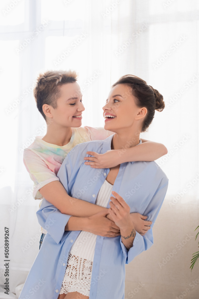 joyful bigender people embracing and smiling at each other at home. joyful bigender people embracing and smiling at each other at home.