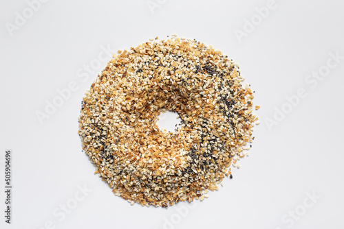 A pile of Everything seasoning containing dried garlic, onion, poppy seeds, sesame seeds and salt on a white background in the shape of a bagel.