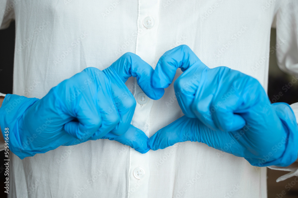 A nurse in blue medical gloves shows her heart A nurse in blue medical gloves shows her heart