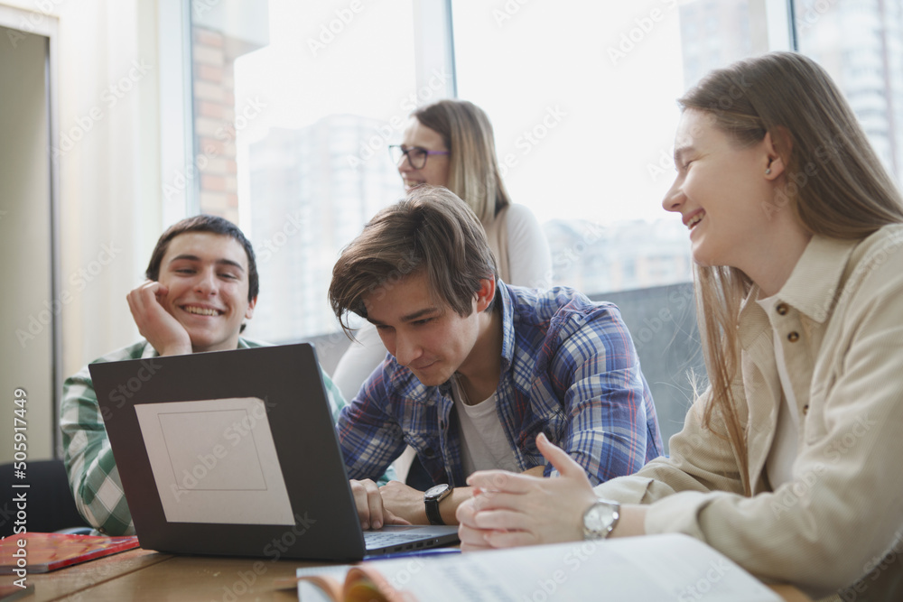 Young people having fun, studying together in college, using laptop in class Young people having fun, studying together in college, using laptop in class