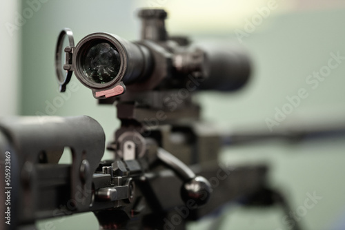 Detail view of the telescope part of a military weapon sniper placed on a tripod. Army weapons industry.