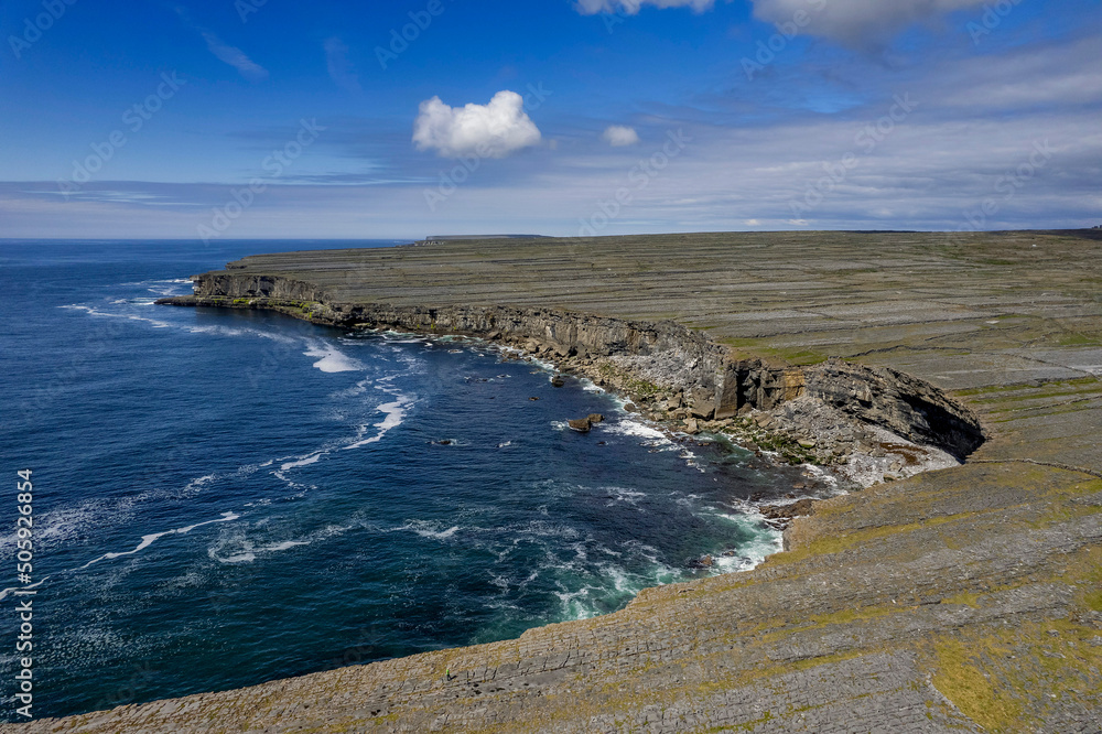 Ocean and cliffs and rugged stone terrain of Aran Island. Warm sunny day and blue cloudy sky. Popular travel tourism destination. Irish landscape. Ocean and cliffs and rugged stone terrain of Aran Island. Warm sunny day and blue cloudy sky. Popular travel tourism destination. Irish landscape.