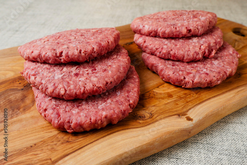 Six simple beef uncooked burgers on a wooden board. Meat industry product. Fast fool meal.