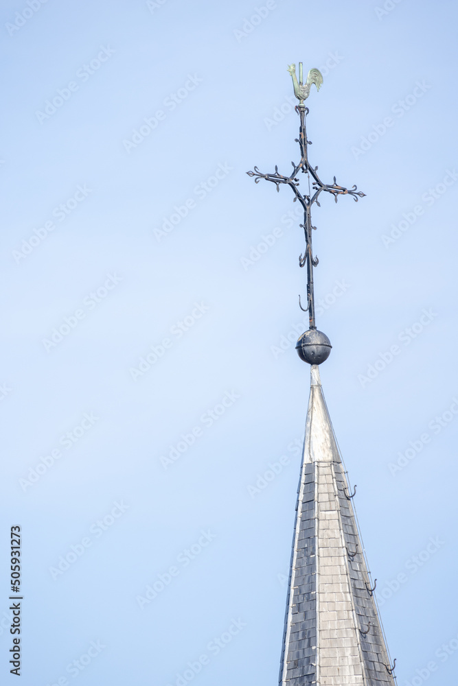 The cross on the spire of the church against the background of the sun and clear blue sky The cross as a symbol of faith in God. High quality photo