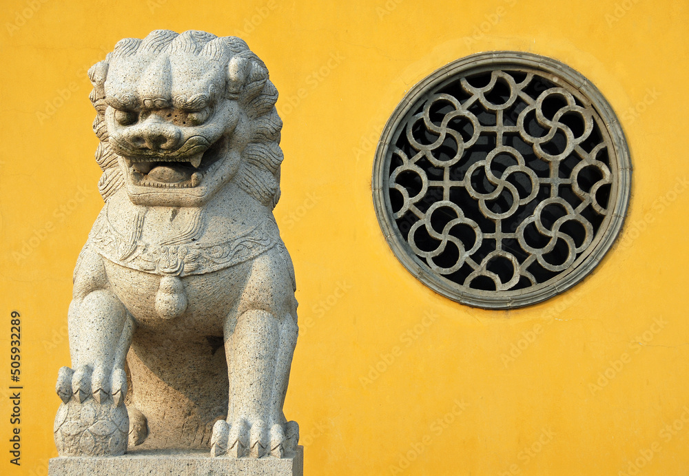 Φωτογραφία Zhenjiang, Jiangsu Province, China: A traditional Chinese lion statue against a yellow background and circular window at Dinghui Temple in Zhenjiang