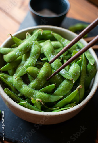 Close-up of steamed edamame sprinkled with sea salt on a dark stone board