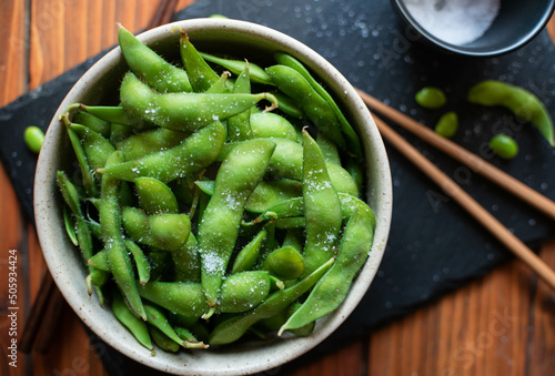 Steamed edamame sprinkled with sea salt on a dark stone board, top view photo