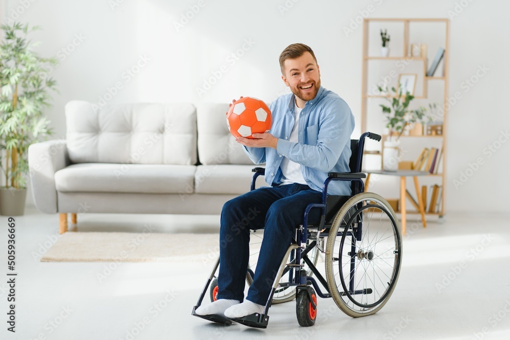Disabled man in wheelchair holding ball with sadness, cannot play game, feeling depressed at home. Disabled man in wheelchair holding ball with sadness, cannot play game, feeling depressed at home.
