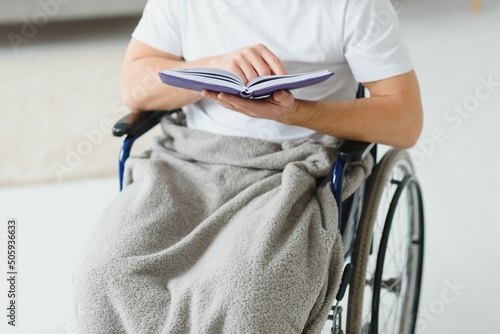 man in wheelchair reading a book at home