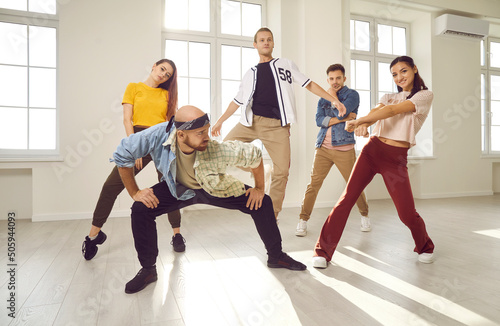 Group of happy young people dancing in the studio. Team of contemporary or hip hop dancers in casual wear practising a new choreo together. Modern dance concept