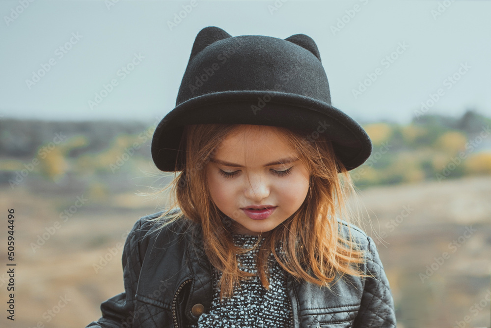 Caucasian little girl in a black hat close-up, stylish and fashionable children