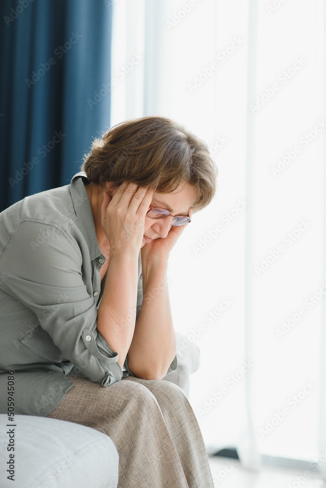 Elderly senior woman massaging her temples to reduce her headache. Older lady feeling scared, anxious, and thinking of sickness or mental health while suffering from a severe migraine or memory loss Elderly senior woman massaging her temples to reduce her headache. Older lady feeling scared, anxious, and thinking of sickness or mental health while suffering from a severe migraine or memory loss