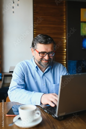 Senior male freelancer working on laptop in cafe. remote work concept.