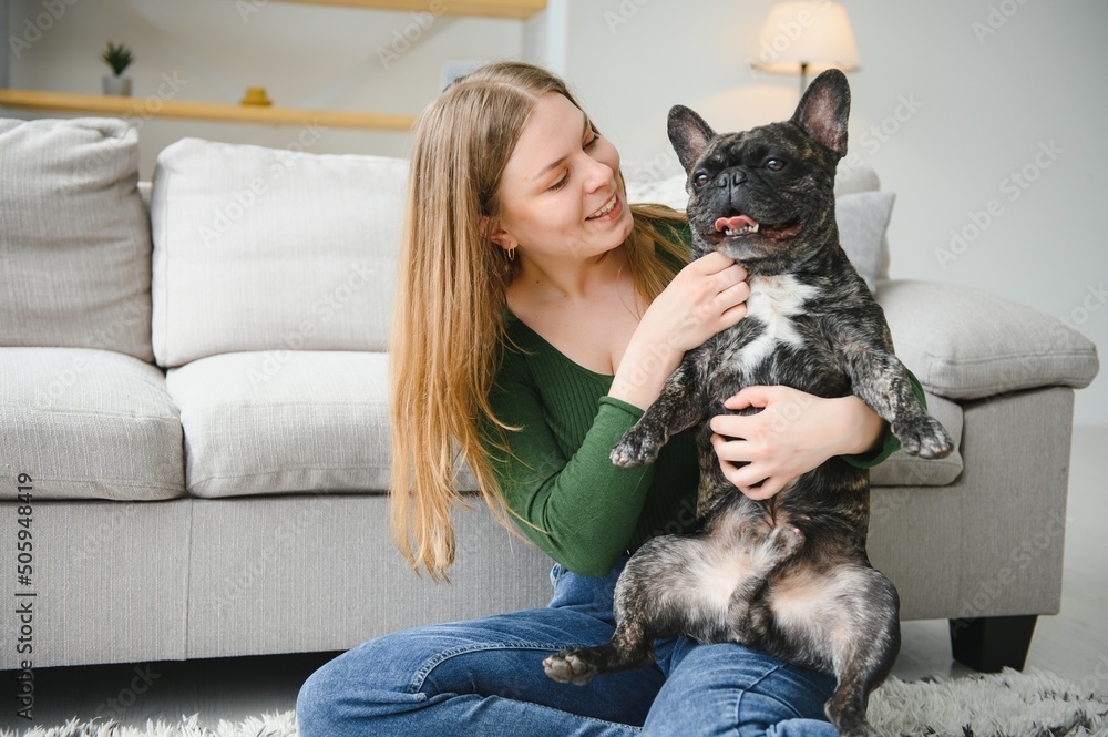 beautiful girl, smiling and sitting on floor near French bulldog