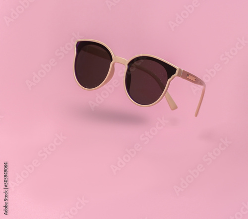 Soaring trendy sunglasses on pink background with shadow