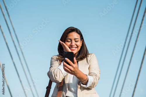 Close-up of Latina woman entrepreneur leader expert economist financier happy to receive an award, receives notification on cell phone