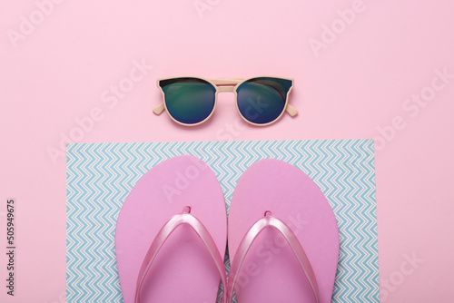 Vacation concept. Sunglasses and flip flops on blue pink background. Top view. Flat lay