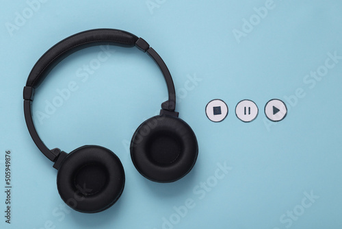 Stereo headphones with icons start, stop, pause of media player on blue background. Top view