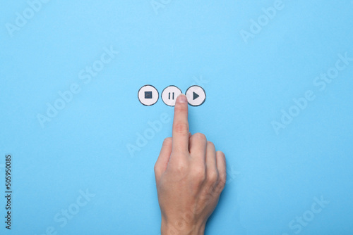 Hand presses pause media player icon on blue background photo