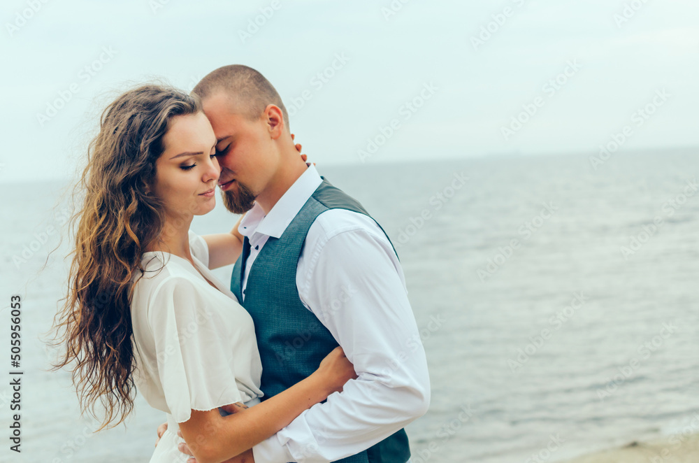 man and woman hugging by the sea on their honeymoon