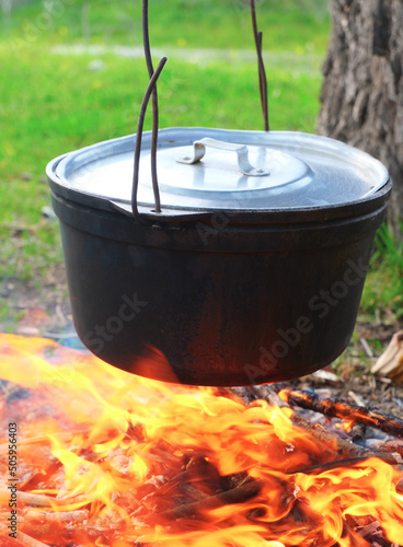 Hiking pot, Bowler in the bonfire. in cauldron at the stake. Traveling, tourism, picnic cooking, cooking at the stake in a cauldron, fire and smoke.