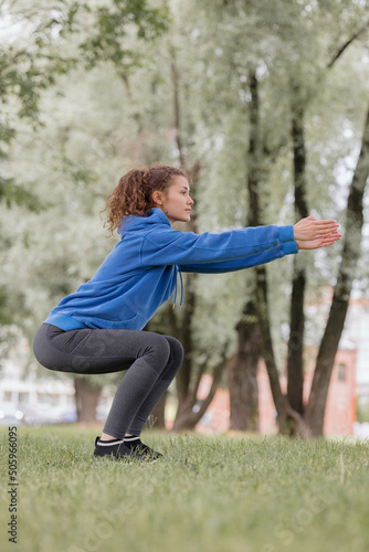 a European woman does sports in a park or a public place. warm-up and jogging in the fresh air, physical exercises for health and beauty. yoga and meditation for mental health. a young adult woman is