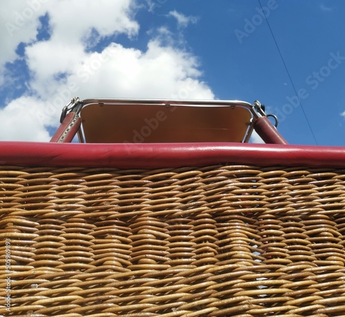Hot air balloon wicker basket from below against blue cloudy sky