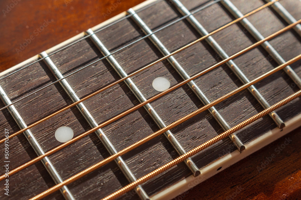Guitar neck, stretched strings, frets and texture of natural material neck with selective shallow focus and blur. Guitar neck, stretched strings, frets and texture of natural material neck with selective shallow focus and blur.
