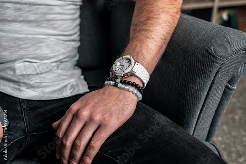 Stylish dark and light bracelet made of natural stones and minerals on a male hand, with a white watch, close-up