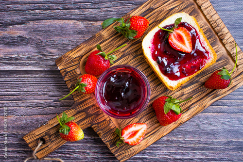 Strawberry jam in a glass of bread on an old background