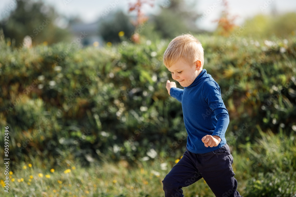 Little child boy running forward in the big green grass field summer day. kid freedom concept. Little child boy running forward in the big green grass field summer day. kid freedom concept.