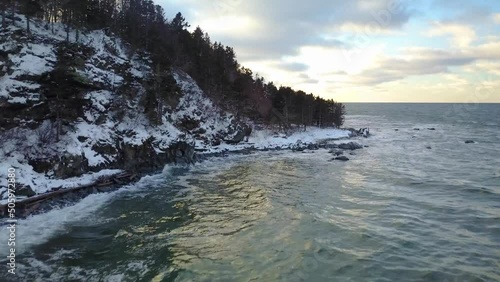 Shot clip captured on drone of the jagged coastline with bare trees and snowy ground during midwinter in Sainte Anne des Monts, Quebec, Canada. photo