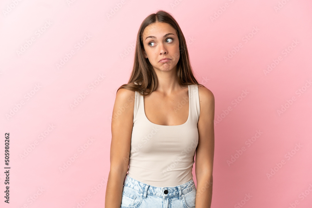 Young woman over isolated pink background making doubts gesture looking side Young woman over isolated pink background making doubts gesture looking side