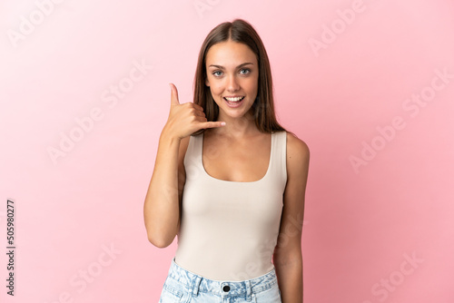 Young woman over isolated pink background making phone gesture. Call me back sign