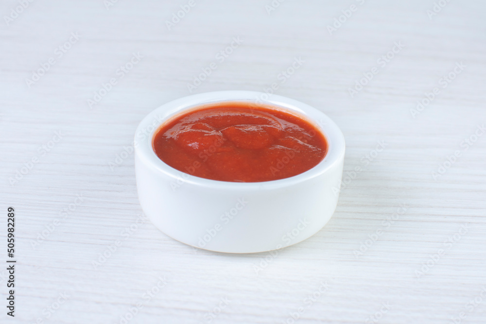 Tomato sauce, in white ceramic bowl on white wooden background Tomato sauce, in white ceramic bowl on white wooden background