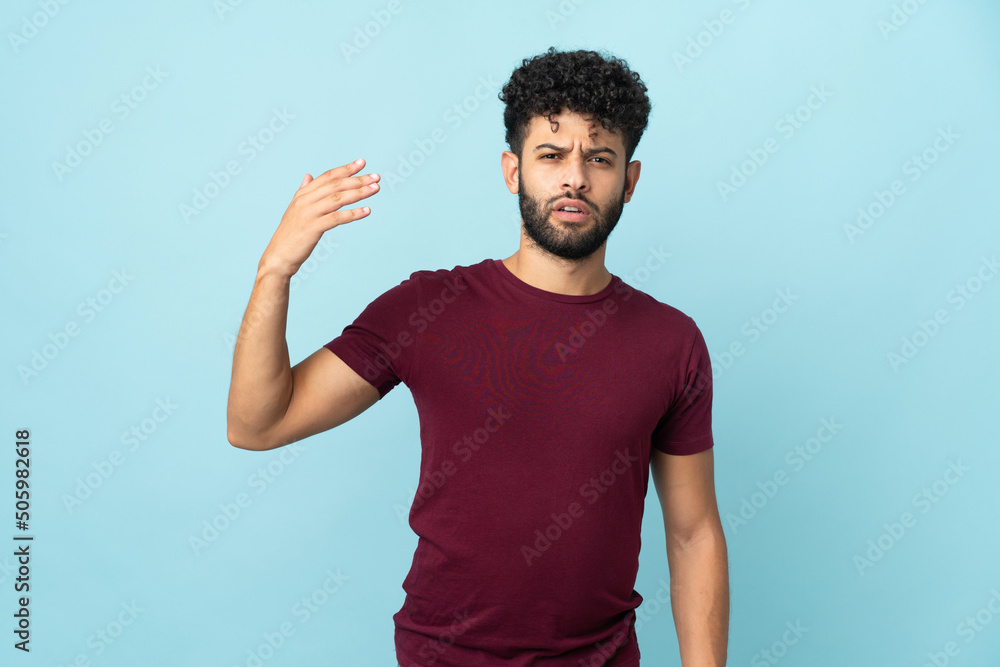 Young Moroccan man isolated on blue background with tired and sick expression Young Moroccan man isolated on blue background with tired and sick expression