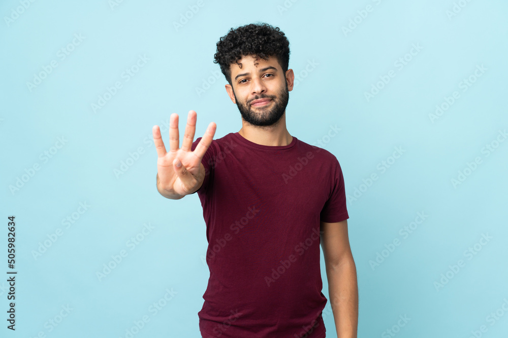Young Moroccan man isolated on blue background happy and counting four with fingers Young Moroccan man isolated on blue background happy and counting four with fingers