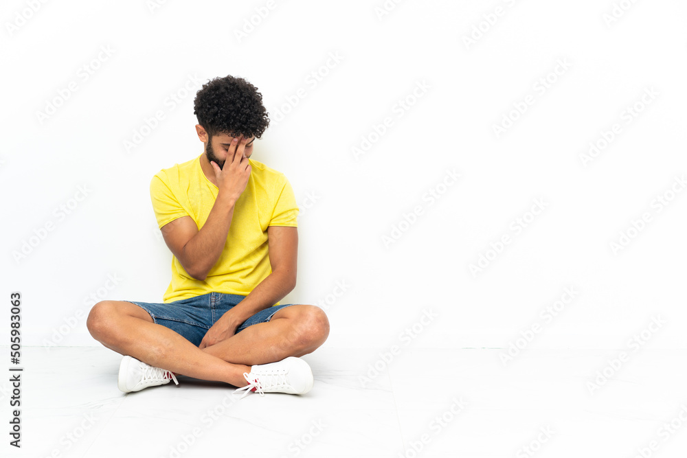 Fototapeta premium Young Moroccan handsome man sitting on the floor over isolated background laughing