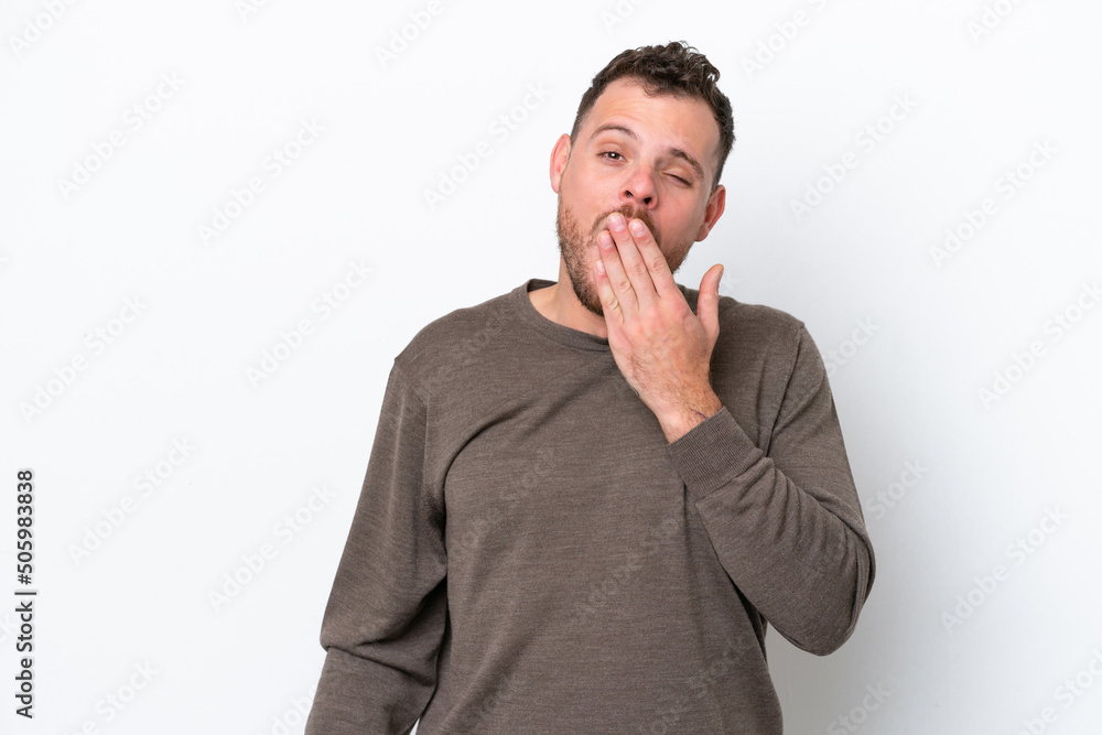Young Brazilian man isolated on white background yawning and covering wide open mouth with hand Young Brazilian man isolated on white background yawning and covering wide open mouth with hand