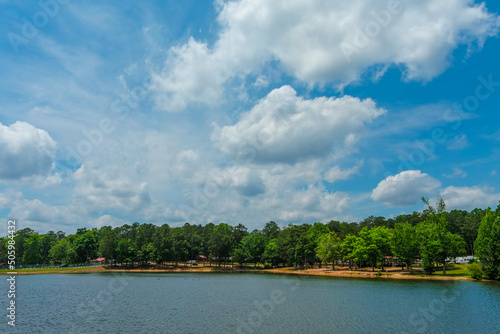 a gorgeous blue rippling lake surrounded by lush green trees, grass and plants with a gorgeous blue sky and powerful clouds at Lake Spivey Recreation Center in Jonesboro Georgia USA photo