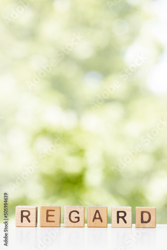 Regard word or concept represented by wooden letter tiles on green summer background