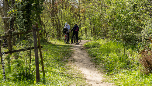 Young teenagers cycling on a grassy path, from behind, in the spring © Natura