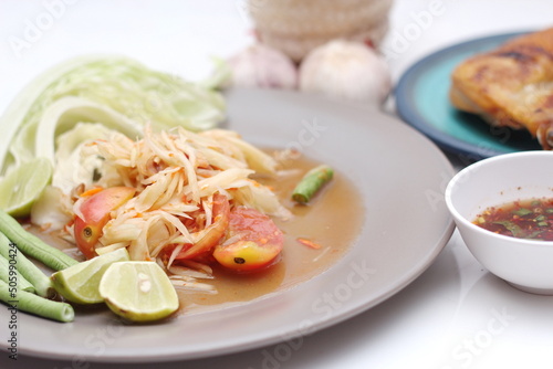 Thai papaya salad or what we call " Somtum " in Thai. The famous local Thai street food dish with the taste of hot and spicy on White table.
