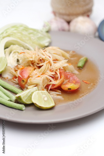 Thai papaya salad or what we call " Somtum " in Thai. The famous local Thai street food dish with the taste of hot and spicy on White table.