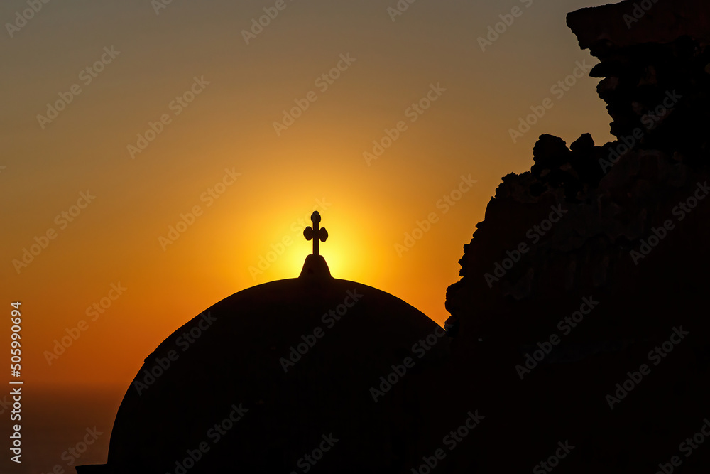 Silhouette of church dome with a cross during sunset.