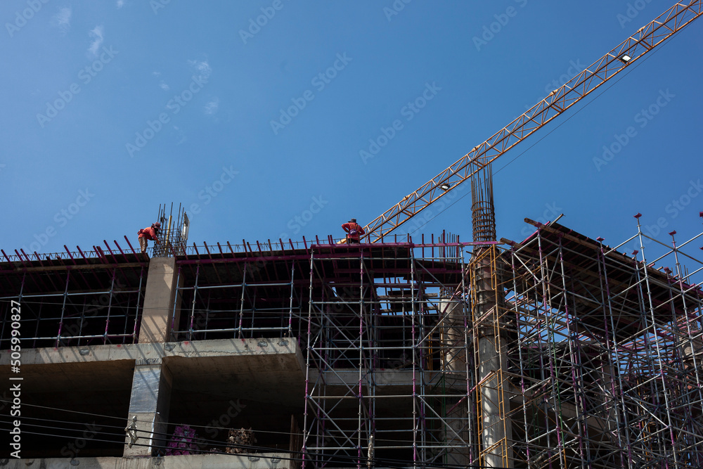 Bottom view of a building under construction against a clear sky background.