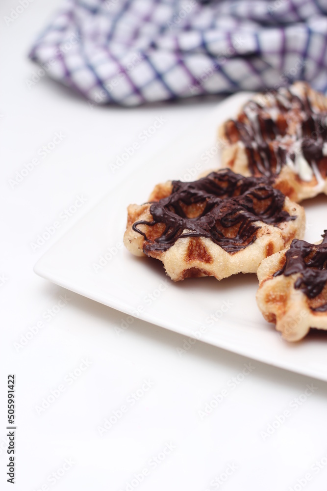 Waffles topped with chocolate and strawberries served in a white plate. Waffles topped with chocolate and strawberries served in a white plate.
