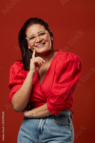 mujer guapa joven  colombiana mirando a la camara soniendo en un fondo rojo con espacio para copy